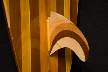 Close-up of a laminated wooden fin set against the striped board